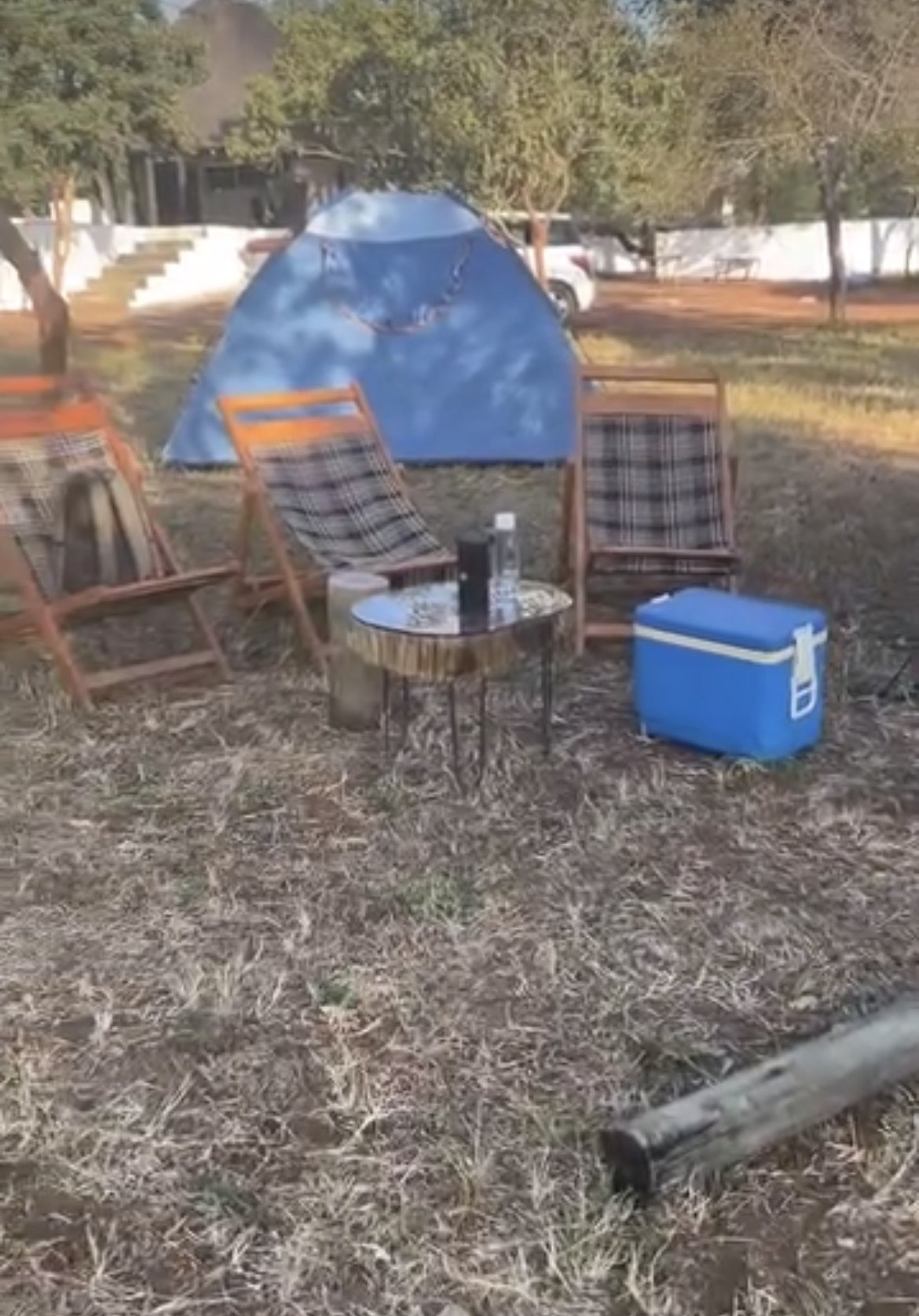 Camp chairs, table, and cooler set up at a campsite